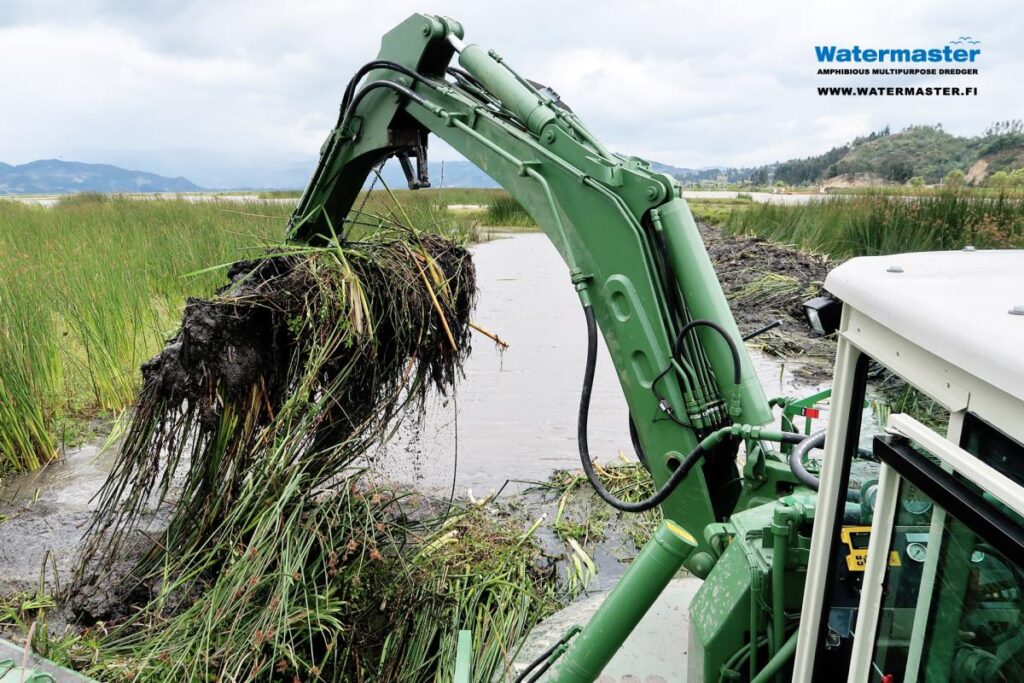 Watermaster dredger removing invasive vegetation from a lake by raking