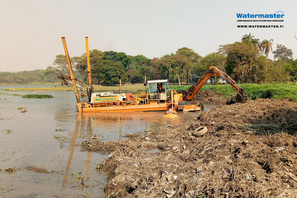 Watermaster clearing sludge, trash, and invasive vegetation from the Tshombe Lake to improve water flow and prevent flooding in D.R. Congo