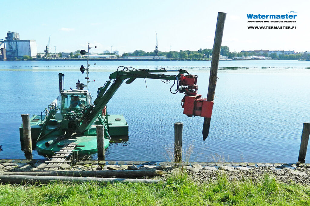 Watermaster dredger reinforcing the banks of an urban waterway by pile driving.